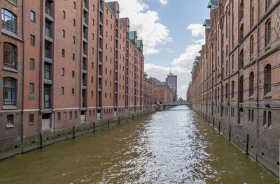 Canal amidst buildings in city against sky