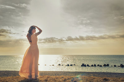 Woman standing at beach against sky