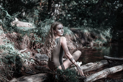 Young woman sitting on tree in forest