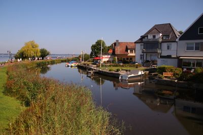 Houses by lake and buildings against sky