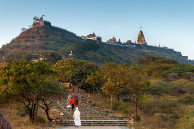 People on building by mountain against clear sky