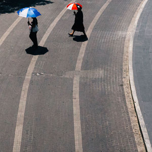 High angle view of people holding umbrellas walking on street ion city