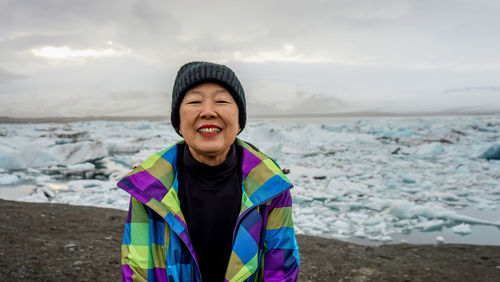 Portrait of smiling woman standing by frozen lake