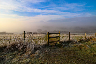 Wooden fence on field against sky