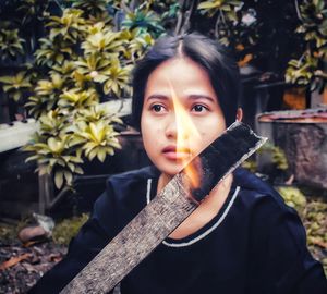 Portrait of beautiful young woman against tree