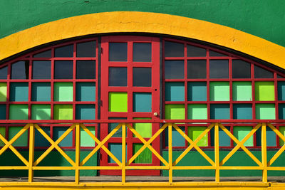 Colorful geometric window panes, red door, yellow trim, green building in baja, mexico