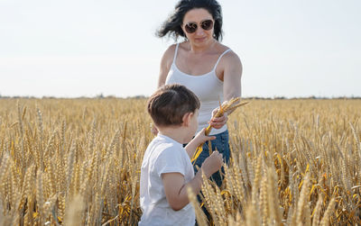 Happy family on a summer walk, mother and child walk in the wheat field and enjoy the beautiful 