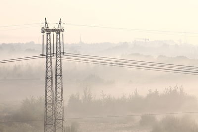 Electric pylon in foggy sunrise