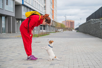 Woman with dog on footpath in city