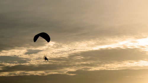 Low angle view of silhouette person flying against sky during sunset