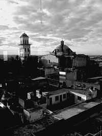 Buildings in town against cloudy sky