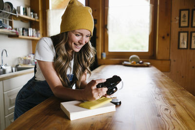 Happy woman with camera leaning on kitchen counter