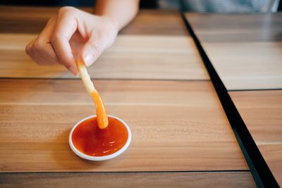 Close-up of hand dipping french fry in sauce