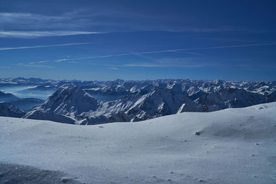Scenic view of snowcapped mountains against blue sky
