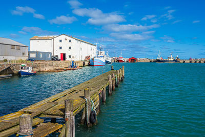 Pier over sea against blue sky in city