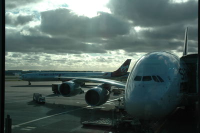 Airplane at airport runway against sky