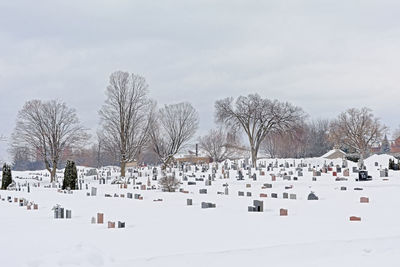 Snow covered cemetery against sky