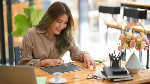 Smiling businesswoman using digital tablet at cafe
