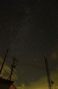 Low angle view of silhouette electricity pylon against sky at night