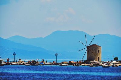 Traditional windmill by mountain against sky