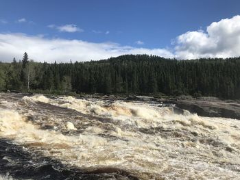 Scenic view of river flowing against sky