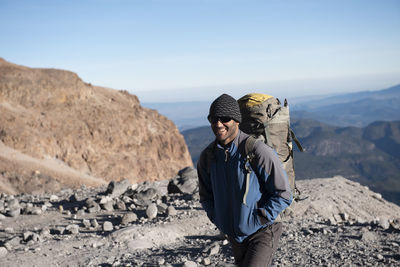 Young man on rock against sky