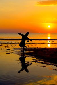 Silhouette of people on beach at sunset