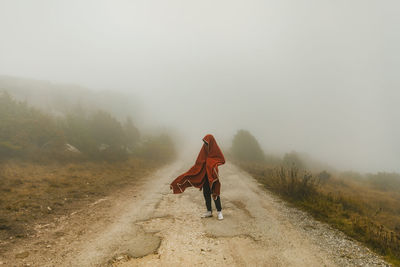 Man covered in blanket standing on road