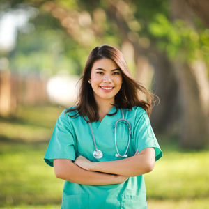 Portrait of smiling female doctor with arms crossed standing outdoors