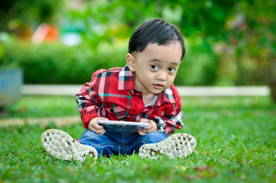 Portrait of cute boy sitting on grass