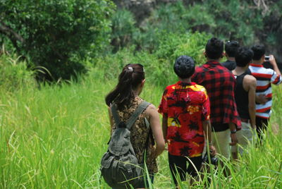Rear view of people on grass against trees