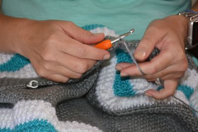 Midsection of woman knitting wool at home