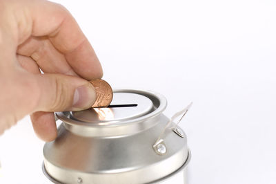 Close-up of hand holding cup over white background