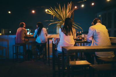 Rear view of people sitting in restaurant at night