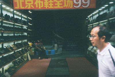 Side view of man looking at illuminated restaurant