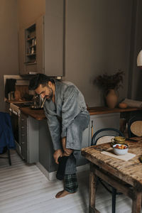 Man removing sock while brushing teeth at home