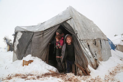 A syrian refugee child at the door of his snow covered tent