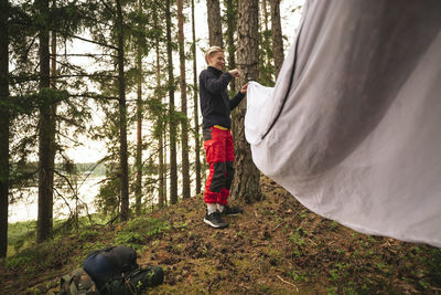 Female hiker pitching tent in forest