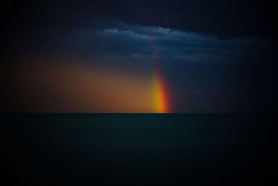 Scenic view of rainbow over sea against sky