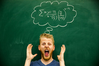 Man gesturing with mathematical formula on blackboard