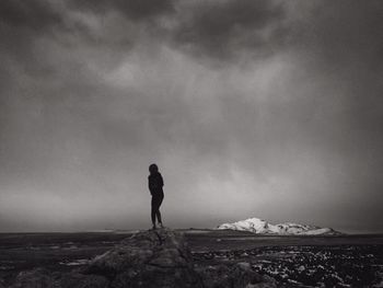 Silhouette woman standing on rock against sky