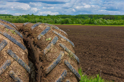 Dirty double wheels of agriculture tractor at sunny summer day with plowed field in the background