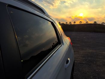 Cropped image of car on road at sunset