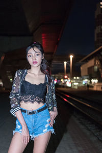 Young woman standing against illuminated lights at night