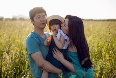 Korean family mom and father with a girl child daughter with candy lying on a green field in summer