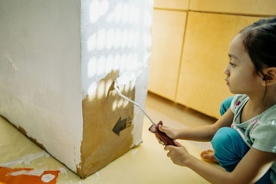 Side view of girl sitting at home