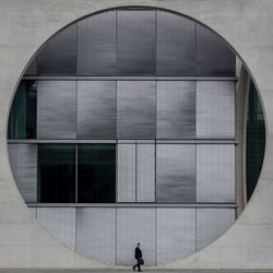 Businessman walking against patterned building