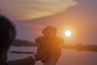 Portrait of woman holding sun against sky during sunset