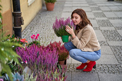 Full length of woman sitting on purple flowering plant