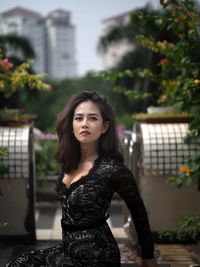 Portrait of young woman standing against building